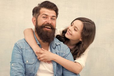 Çocuk sevilive önemsenmiş hissediyor. Mutlu küçük çocuk kızı ve baba sevinçle gülümsüyor. Küçük kız çocuk gri arka plan üzerinde baba sarılma. Mutlu bir çocuk yetiştirmek