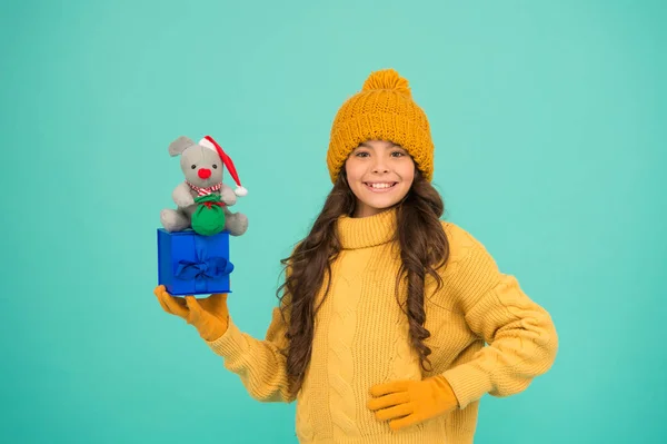 Çocuklar için alışveriş. Mutlu 2020 yılları. İyi şans için bir hediye. Başarılı fare yılı. Hediyeyle eğlen. Alışveriş ipuçları. Mutlu kız fare oyuncağı ve paketlenmiş hediye kutusu tutuyor. Çocuk süveter ve şapka örüp pelüş oyuncak oynuyor. — Stok fotoğraf