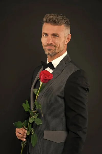 妇女节快乐。优雅的男人拿着红玫瑰在沃姆日。穿着正式西装的帅哥和黑色蝴蝶结庆祝妇女节。3月8日或国际妇女日庆祝活动 — 图库照片