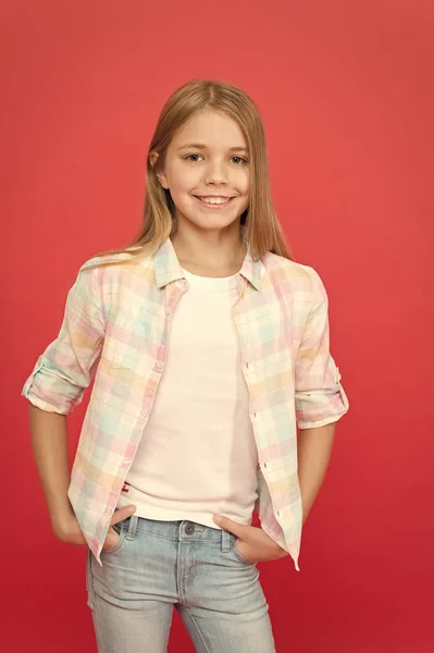 I sin egen stil. fashionabla lilla flickan. Kid mode. snygg skönhet. liten flicka röd bakgrund. lycklig barndom. leende blondin unge. barnflicka med långt blont hår. avslappnad stil. barnens dag — Stockfoto