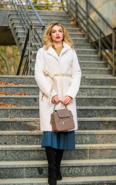 Modern sıcak ve şık eko kürklü giysi. Sıcak palto giyen kız şehir arka planında. Rahat ve güzel hissetmek için sonbahar kıyafeti yap. Kadınlar şık kıyafetler giyer ve çanta taşırlar. Sonbahar kıyafeti