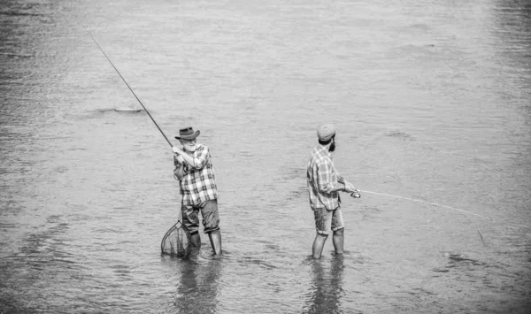 Amizade masculina. Pescando pai e filho. Fim de semana. Pescador feliz com vara de pesca e rede. Atividades hoteleiras e desportivas. A pescar juntos. Os homens estão na água. Pesca é muito mais do que peixe — Fotografia de Stock