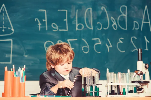 Experimento educativo. Feliz infancia. Niño cerca de microscopio y tubos de ensayo aula de la escuela. Concepto de conocimiento. Día del conocimiento. Estudia biología química para niños. Conocimientos básicos Educación primaria — Foto de Stock