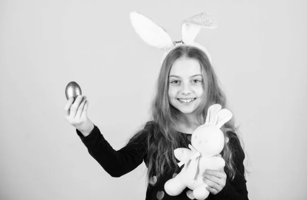 Frühjahrsferien. Ostereiersuche im Rahmen des Festes. Mädchen kleines Kind Osterhasen Accessoire halten gefärbte Eier. Herkunft des Osterhasen. Ostersymbole und Traditionen. spielerisches Kind mit Stofftier — Stockfoto