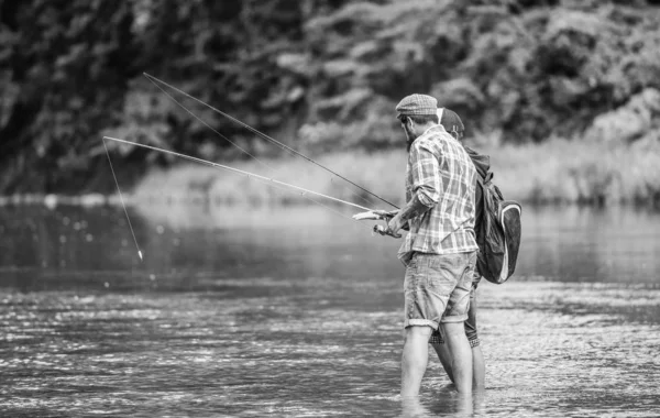 Τέλειος τρόπος για να περνάς χρόνο έξω με την οικογένεια και τους φίλους σου. Οι άντρες ψαρεύουν. Η οικογένεια των αλιέων στο ποτάμι. Καλάμι. Εξοπλισμός ψαρέματος. Άθλημα για χόμπι. Ψάρεμα με περιστρεφόμενο τροχό. Ψάρεμα ειρηνική δραστηριότητα — Φωτογραφία Αρχείου