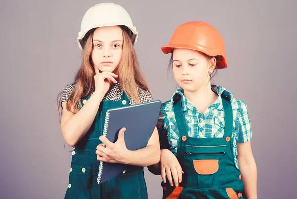 Kislányok, akik együtt javítanak a műhelyben. Foreman felügyelő. Javítás. Kisgyerekek sisakban táblagéppel és görgővel. A munka napja. Május 1. Mérnöki ötlet. Házi gondok. vállalkozó — Stock Fotó