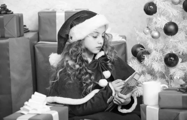 Niña mantenga pluma y papel cerca de árbol de Navidad y caja de regalo. Cree en el milagro. Envía una carta a Santa. Lista de deseos. Disfraz de niño santa disfrutar de la víspera de Navidad. Niño escribe carta a Santa Claus. Querido Santa — Foto de Stock