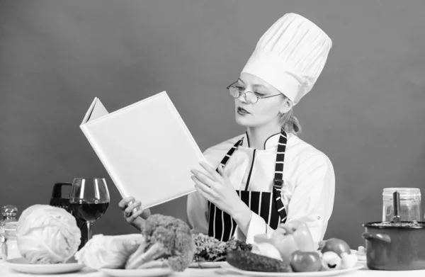 Yemek pişirme ve sağlıklı vejetaryen menü sunmaktadır. Mutfak masasında Güzel kadın aşçı okuma menü kartı. Sevimli kadın bir gün için restoran menüsü öğrenme. Menü yiyecek ve içecek listesi — Stok fotoğraf