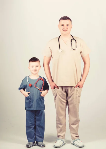 Father doctor with stethoscope and little son physician uniform. Future profession. Want to be doctor as dad. Cute kid play doctor game. Family doctor. Pediatrician concept. Medicine and health care — Stock Photo, Image