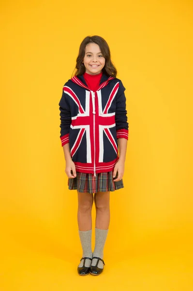 Culture and customs. Small girl school uniform. English student. Education and upbringing. Language school. English kid yellow background. Learn english language. British accent. Great Britain flag