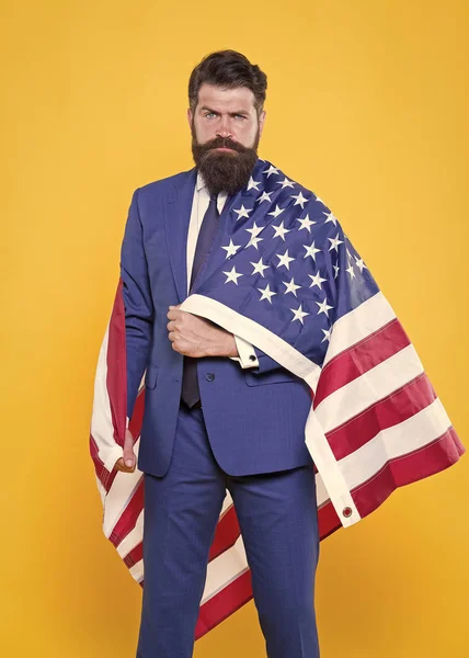 Flaggan är hans stolthet. Skäggiga mannen innehar amerikanska flaggan på självständighetsdagen. Patriotiska affärsman firar flagg dag. Säker hipster i Formalwear med Förenta staternas nationella flagga — Stockfoto