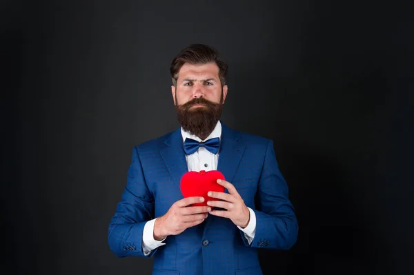Happy valentines day. tuxedo man with red heart. love and romance. ready for date. brutal bearded hipster in formal outfit. confident and successful businessman in suit with bow tie — 스톡 사진