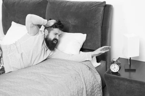 Odio el ruido del despertador. tiene un terrible dolor de cabeza. Hombre en casa. Concepto de salud. necesita más descanso en la cama. hombre estresado e infeliz. El hombre barbudo hipster quiere dormir. despertar temprano en la mañana —  Fotos de Stock