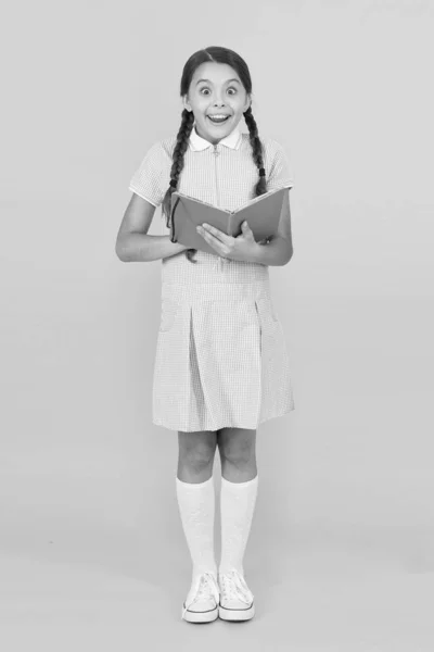 Fascinerande historia. liten flicka älskar litteratur. gamla skolan. lycklig liten flicka i retro uniform. Vintage Kid mode. tillbaka till skolan. liten flicka hålla arbetsboken eller märka. uppslagsverk för barn — Stockfoto