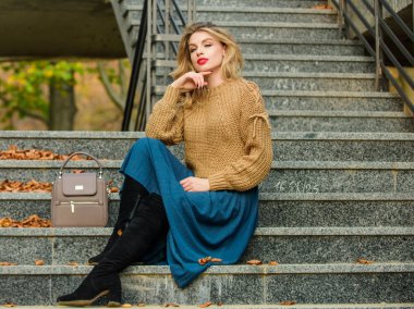 Düşüncelere daldım. Sıradan stil öğrencisi. Sonbahar sezonu. Etek ve süveter giyen kız. Pileli trend. Kadın güzeli. Moda modeli. Sonbahar kadını dışarıda kıvırcık saçlı. Uzun sarı saçlı kız merdivenleri.