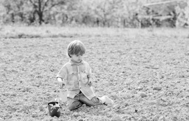 Bahçede küçük yardımcı. Çocuk alanda zemin Ekim çiçek oturup. Çiftlikte eğlenceli zaman. Bahçe konsepti. Çocuk küçük kürek ve pot bitki ile eğlenin. Fidanları dikmek. Sahada dikim