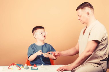 Çocuk küçük doktor masa tıbbi aletleri oturup. Sağlık. Tıbbi muayene. Çocuk sevimli çocuk ve babası doktor. Hastane çalışanı. İlk yardım. Tıbbi yardım. Travma ve yaralama. Tıp kavramı