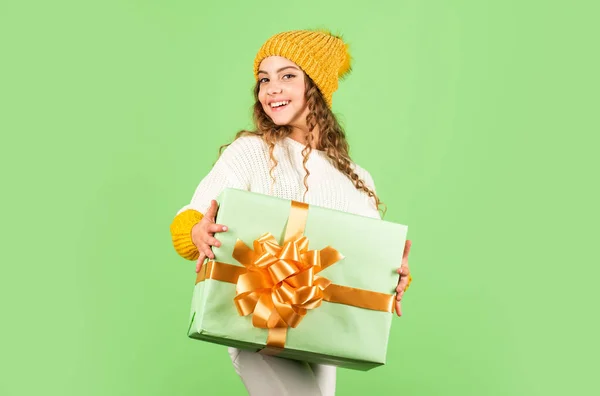 Τι μεγάλη έκπληξη. εκπτώσεις για χειμερινές διακοπές. χαρούμενο κοριτσάκι πλεκτό καπέλο και πουλόβερ. παιδί κρατήσει το παρόν κουτί πράσινο φόντο. Ευτυχισμένο το νέο έτος. Χριστουγεννιάτικο παζάρι. Καλά Χριστούγεννα και σε σένα — Φωτογραφία Αρχείου