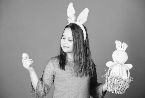 Elle commence sa chasse aux œufs de Pâques. Petite fille tenant oeuf de Pâques et lapin jouet. Petit enfant avec œuf coloré et lapin dans le panier de Pâques. Enfant mignon portant des oreilles de lapin dans le style de Pâques — Photo