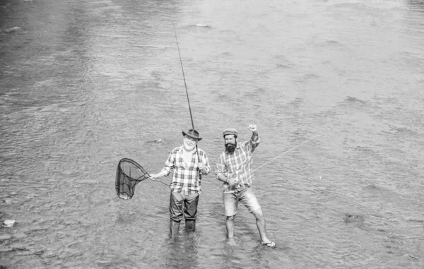 Equipo de pesca. Pescador feliz con caña de pescar y red. Hobby y actividad deportiva. Amistad masculina Padre e hijo pescando. Fin de semana. Pescando juntos. Los hombres están en el agua. Buen concepto de captura —  Fotos de Stock