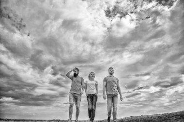 Birleşik grup kasıtlı ilerleyecektir. Erkek ve kadın yürüyor dramatik bulutlu gökyüzü arka plan. Gerçek dostluk kader engellerle büyümek. Üçlü gerçek arkadaşlar Birleşik. Yalak devam uzun bir yol