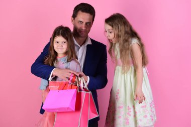 Şaşırmış yüzlü kızlar ve erkekler alışveriş torbalarını tutarlar.