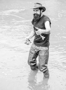 Acımasız adam nehir suyunda dikilir lastik çizmeler giyer. Fisher hafta sonu aktivitesi. Balıkçı ekipmanları ile Fisher. Kancadaki balıklar. Vahşi doğada eğlence. Balık tutmanın eğlencesi yakalamaktır. Balıkçılık erkeksi hobi