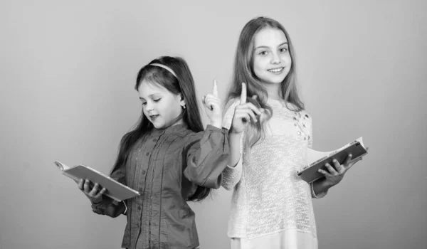 Enfants filles avec des livres ou des blocs-notes. Éducation et littérature pour enfants. Conte de fées préféré. Je retourne à l'école. Les sœurs choisissent des livres à lire ensemble. Adorables filles aiment les livres. Ouvrir les portes par l'alphabétisation — Photo