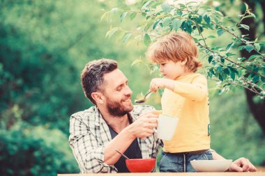 Yaz kahvaltısı. Sağlıklı gıda konsepti. Baba oğul yemek yer ve eğlenir. Bebeği besliyorum. Çocuklar için menü. Aile ev yapımı yemeğin tadını çıkarır. Yemek alışkanlıkları. Babasıyla yemek yiyen küçük bir çocuk.
