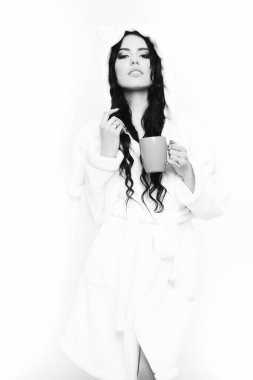 Fincanlı bej kadife bornozla poz veren seksi kız.