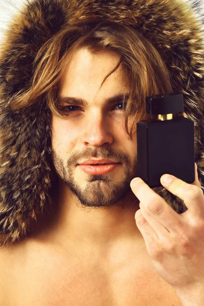 Homem macho barbudo em casaco de pele segurando frasco de perfume — Fotografia de Stock