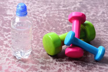 Plastik su şişesi Bordo arka plan üzerinde yakınındaki halter