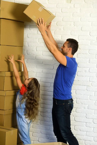 Daughter puts hands up and father puts boxes in pile