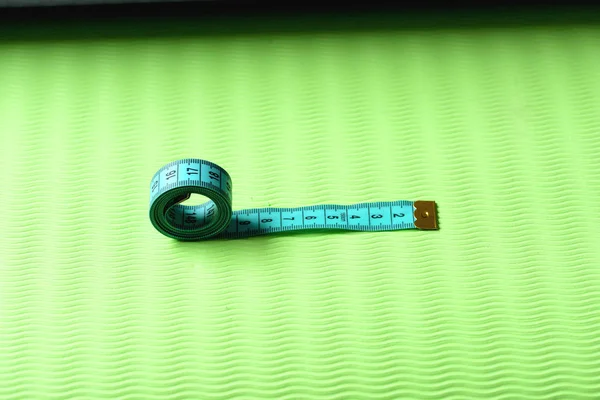 Rollo de cinta métrica en color cian sobre fondo de textura verde — Foto de Stock