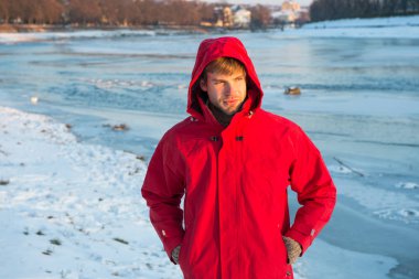 Kutup kaşifi. Güneşli kış günü. Kış erkek giyim. Kış kıyafeti. Rahat bir kıyafet. Erkek ceketi. Sıcak ceketli, karlı bir arka plan. Rüzgara dayanıklı kıyafetler. Kışın balık. Güvenlik önlemleri