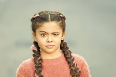 Yanlış olan ne? Şaşkın bakışlı küçük bir çocuk. Küçük çocuk uzun esmer örgüler takıyor. Sıradan moda tarzında sevimli bir çocuk. Dışarıdaki sevimli kız çocuğu. Çocukluk. Uluslararası Çocuk Günü