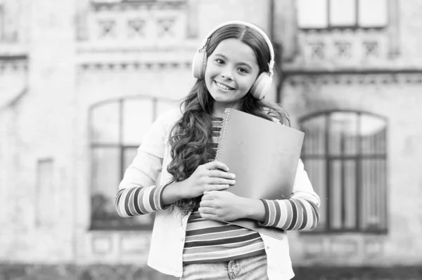 Curso de audio. Tecnologías digitales para el aprendizaje. Colegiala mantenga libros de trabajo y auriculares. Tecnologías para estudiar. Tecnologías modernas. Elearning y métodos modernos. Escuchar el libro escolar — Foto de Stock