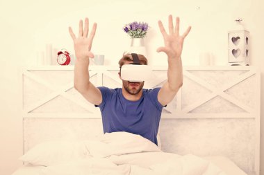 En iyi sanal gerçeklik deneyimi. Yatakta VR kulaklık takan yakışıklı adam. Beyaz adam yatak odasında sanal gerçeklik gözlüğü kullanıyor. VR içerisindeki etkileyici canlandırma