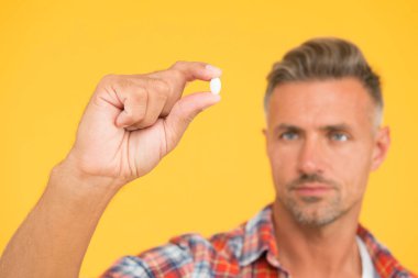 Elimde vitamin hapı var. Yan etkiler. İlaç konsepti. Kenevir türevi CBD. Erkek sağlığı için gıda katkı maddeleri. Vitamin kompleksi. Yakışıklı, olgun bir adam ürününü sunuyor. Uyuşturucu hapları yakında.