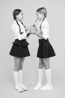 Turuncu en sağlıklı sıvıdır. Küçük kızlar sarı arka planda portakal meyvesuyu içiyor. Küçük okul çocukları sulu turuncu atıştırmalık ların tadını çıkarıyorlar. Vitamin dolu portakal suyu