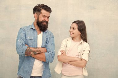 Mutlu ol ve gülümse. Mutlu bir aile. Mutlu baba ve küçük kızı kollarını gri arka planda çapraz tutmak. Sakallı adam ve küçük çocuk mutlu gülümseyerek.