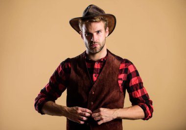 Şapkalı bir kovboy. Batı hayatı. Tıraşsız kovboy bej arka planı. Kovboy şapkalı traşsız adam. Yakışıklı sakallı maço. Amerikan kovboyu. Güzellik standardı. Gerçek erkeklik örneği.