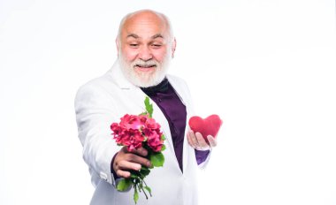 Bu da senin için. Centilmen kavramı. Gerçek bir beyefendi. Yakışıklı sakallı adam smokin giyer. Romantizm ve flört. Yaşlılar için flört hizmetleri. Yaşlı centilmen romantik. Adam aşkın sembolünü taşıyor.