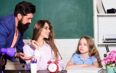 Ödev yapan küçük bir kız. Aşırı korumacı bir aile. Aşırı korumacı ebeveynlik tarzı. Baba anne çocuğa öğretiyor. Zeki bir aile. Aşırı korumacı ebeveynlik tarzının en büyük dezavantajı yetersiz hazırlanmış çocuklar