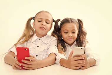 Modern öğrenciler. Sınıfta cep telefonu kullanan küçük öğrenciler beyaz üzerine izole edildi. Küçük öğrenciler ders sırasında mesaj atarlar. Sevimli lyceum öğrenciler akıllı telefon dersleri derin dalış