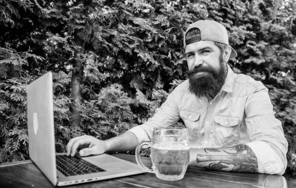 Laptop continua a ajudar os funcionários virtuais. Usuário de laptop bebendo cerveja no café ao ar livre. Homem barbudo a trabalhar no computador portátil. Hipster usando laptop com acesso gratuito à Internet — Fotografia de Stock