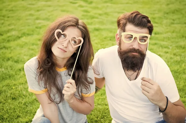 Blijf gefocust met de beste bril. Paar in liefde op zoek door middel van prop bril op groen gras. Sensuele vrouw en hipster houden grappige bril op stok. Vieren met fancy Valentines Party bril — Stockfoto