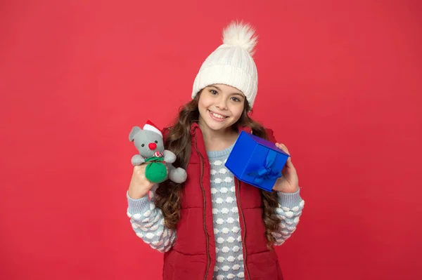 Kerstcadeaus. Vakantie souvenirs concept. Cadeau voor een vrouw. Stuur pakketje. Veel geluk ermee. Bezorgservice. Kerstcadeau idee. Wintervakantie. Happy kid winter outfit houden geschenk doos rood achtergrond — Stockfoto