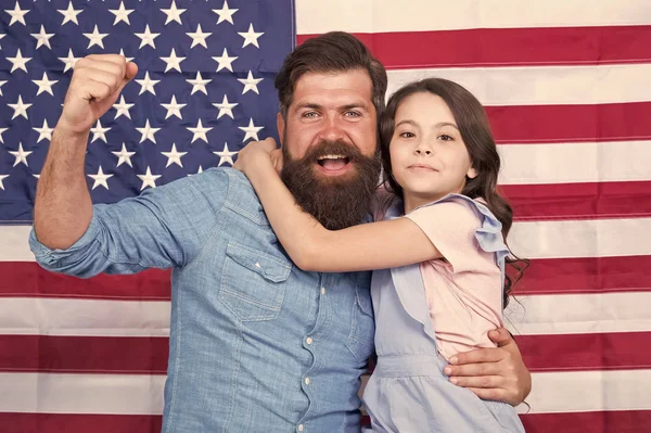 大きな旗に敬意を表します。バナーの装飾で旗の日を祝う愛国的な家族。アメリカの旗の背景に父と小さな娘。あごひげの男と小さな子供と私たちの国旗 — ストック写真