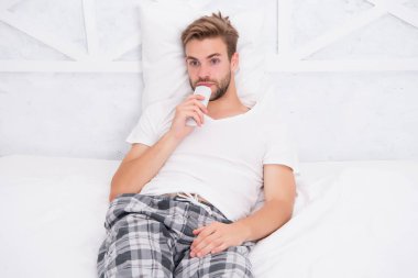 Uzaktan kumandalı pijamalı yakışıklı bir adam. Adam yatak odasında televizyon izliyor. Tembel pazar günü evde. Sabah programını izle. Adam televizyon izliyor. Yatakta uzaktan kumandayla kanal değiştir. Evde yatakta dinleniyor.